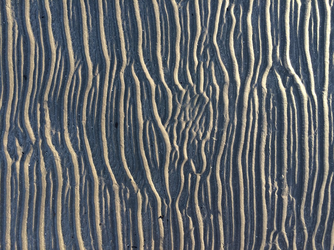 A sand texture with lines of ripples and grooves, resembling wood grain. The dark blue background. –ar 4:3