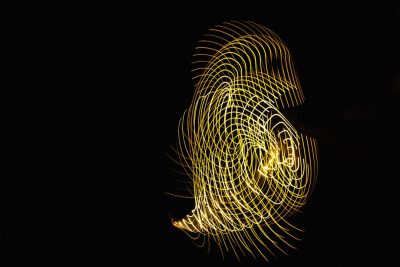 Light painting of an outline in yellow light on black background, creating the shape of eldritch face with swirls and spirals, mysterious mood, high resolution --ar 128:85