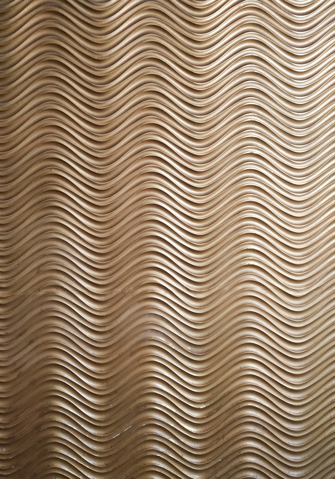 Photo of an abstract wood grain pattern on the wall, with curved lines creating wavy patterns. The light brown background has a textured surface that resembles carved wooden panels, in the style of wood panels. –ar 89:128