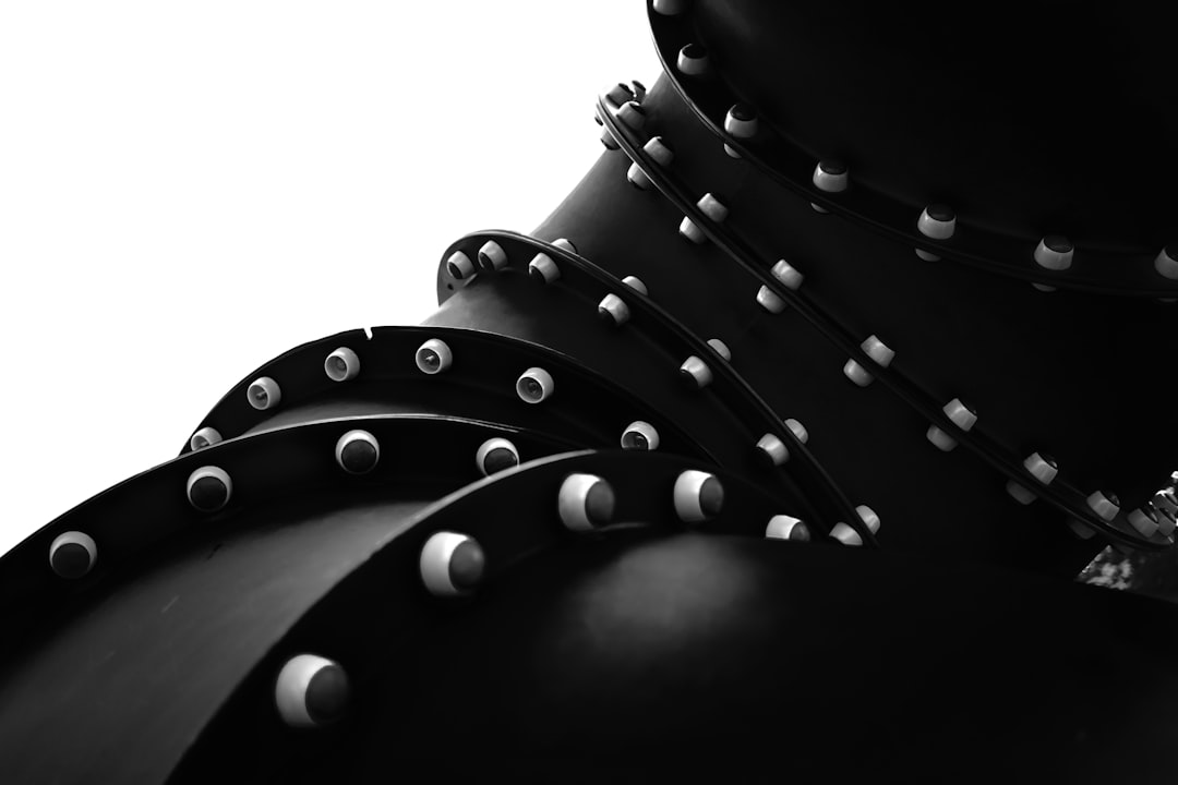 Black and white photo of a large black pipe with metal rivets, an extreme closeup, on a white background, in the style of minimalism, award winning photography. –ar 128:85