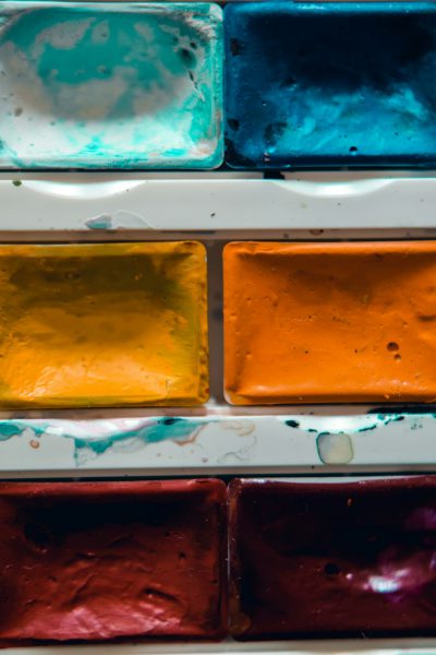 A closeup shot of the watercolor palette, showcasing each color in its separate box with visible edges and the texture of paint inside. The focus is on the rich colors of blue, orange, yellow, green, and red, creating an artistic background for creative projects or as decoration. This detailed photo highlights the beauty and diversity of paints used in the style of artists. --ar 85:128