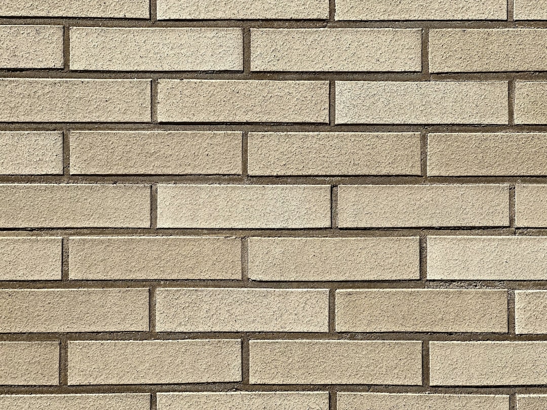 A light beige brick wall with even, uniform blocks creating an elegant and sophisticated background texture. The background is made of rectangular bricks in a straight line pattern, giving it the appearance of traditional masonry or building construction. This design adds depth to any text overlay, making for a classic yet timeless aesthetic. The neutral color tone enhances its appeal as both stylish and professional, suitable for various applications like web backgrounds, graphic designs, etc. –ar 4:3