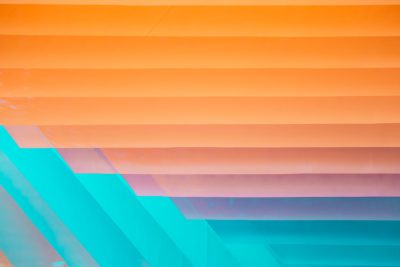 A closeup of the layered paper sheets, with each layer in different shades and colors representing an abstract gradient from orange to teal blue. The layers form a pattern that adds depth and dimension to the composition. --ar 128:85