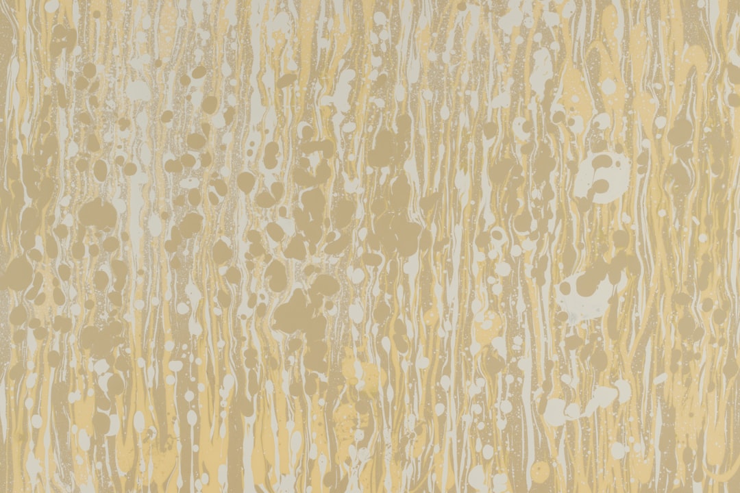 A pattern of light yellow and white, marbled effect, with a pattern of small splashes of ink on the surface. The background is beige. –ar 128:85