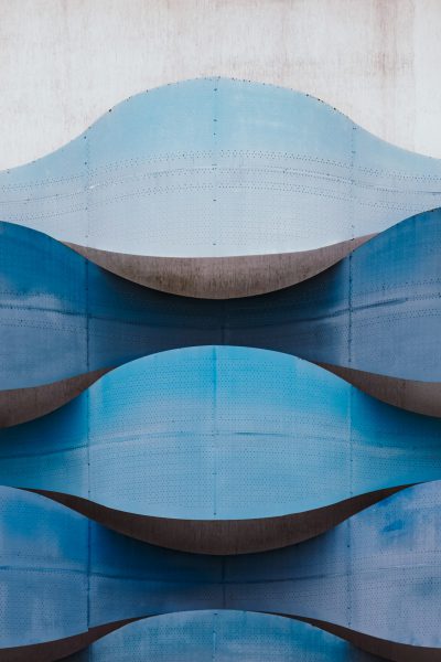 Close up photo of a blue curved wave facade in the style of minimalist architecture against a concrete wall background, in the style of Archdaily photography. --ar 85:128