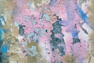 A closeup of an old, peeling wall with pink and blue graffiti. The texture is rough, with visible cracks between the paint layers. This background would be perfect for adding text or illustrations in the style of street art vibes. --ar 128:85