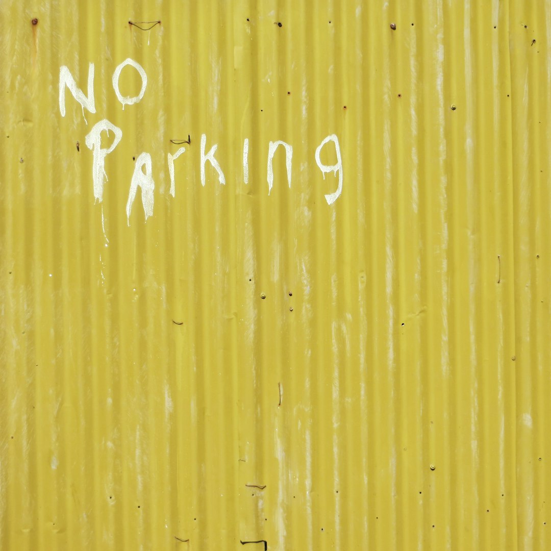 A yellow metal wall with the words “NO parking” written in white paint, front view, full shot, in the style of photography.