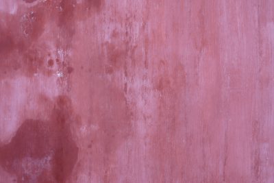 A closeup of an old pink wall with peeling paint, showcasing the texture and weathered appearance. The background is a soft gradient from light to dark red, creating depth in the image. --ar 128:85