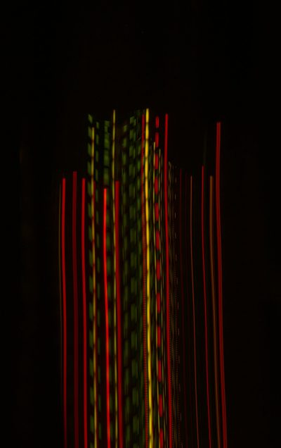 A dark background with red and green lines of light that form the shape of vertical bars, representing music or sound waves. The lights create an abstract pattern in shades of black, yellow, white, and pink. It's a highresolution photo taken from above, with the focus on the lines of light and their effect on darkness. This visual representation creates an atmosphere of movement and energy through the use of lighting effects. --ar 5:8