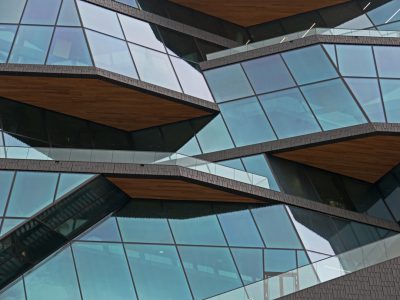 A close up photo of the facade glass and wood paneling on an office building in Amsterdam, in the style of [Zaha Hadid](https://goo.gl/search?artist%20Zaha%20Hadid) with terraces. Photographed using a Canon EOS R6 Mark II camera with an RF 24-70mm lens for its stunning detail and sharpness, ultra realistic. --ar 4:3