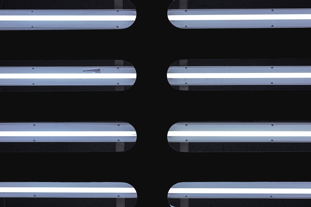 A flat lay of LED tubes on a black background, each panel illuminated with white light and centered in the composition. The lighting creates an illusion that these panels form two horizontal rows, giving depth to the image. –ar 128:85