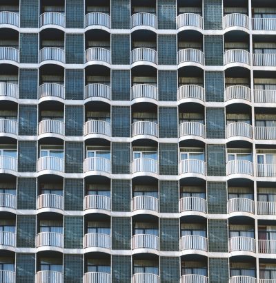 A building facade with symmetrical balconies, each balcony lined up in rows and the windows reflective of their surroundings, creating an abstract patterned effect. The texture is a gridlike arrangement with the balconies forming clear lines across the building's surface. There’s no text or other elements on it. --ar 31:32