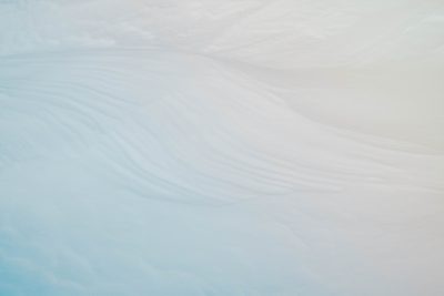 Abstract white and blue background with wavy patterns, closeup of ice on antarctica. Minimalist composition. Soft pastel colors. Low angle shot, macro photography. High resolution. Shallow depth of field. --ar 128:85