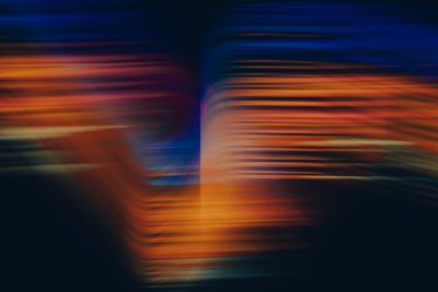 The letter "V" in motion blur, with blurred lines, using orange and blue colors, against a dark background, in the style of photography, with a depth of field effect, in a cinematic style.