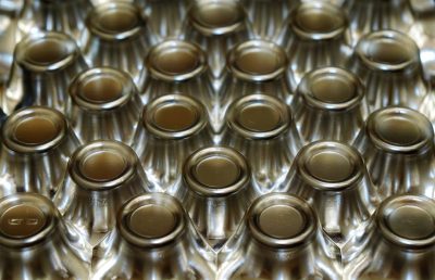 A closeup of the top view of empty glass bottles with metal caps arranged in repeating rows, showcasing their uniform appearance and texture. The bottles are arranged neatly on one side to create symmetry and emphasize their design details. This perspective highlights each bottle's shape and pattern, emphasizing the beauty found within them. The neutral background allows for easy asset design or graphic creations using these bottle images in the style of graphic designers. --ar 64:41