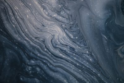 Abstract fluid art background with swirling liquid in dark blue and gray colors. The texture resembles the surface of an ocean or sea, with ripples creating intricate patterns reminiscent of water flow. There is a hint of bubbles on top to add depth and movement. This design would be suitable for creative backgrounds, covers, cards, posters, etc., --ar 128:85