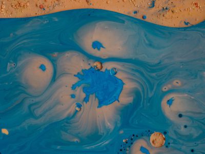 A top view of blue and beige swirling paint, the sand is visible in some places. The water has swirls of light colors with small drops of dark color in the style of an abstract expressionist artist. --ar 4:3