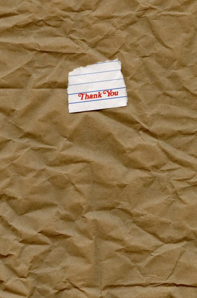 A photo of the text "Thank You" written on a piece of paper, placed on a brown crumpled craft paper background in the style of hyper realistic, high resolution artwork. --ar 21:32