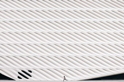 The Broad Museum, Los Angeles, has a white facade with patterned vertical lines. A close up photo shows a person running across the roof. The minimal architecture photography highlights architectural details in the style of the museum. --ar 128:85