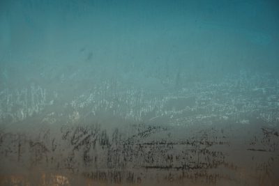 Close up of a foggy window with a blue and teal gradient background, in the style of grunge rough texture, high resolution photography, soft light, neutral colors, misty atmosphere, urban decay, graffiti, in the style of urban art style. --ar 128:85