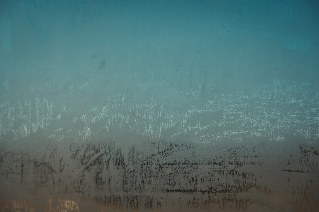 Close up of a foggy window with a blue and teal gradient background, in the style of grunge rough texture, high resolution photography, soft light, neutral colors, misty atmosphere, urban decay, graffiti, in the style of urban art style. –ar 128:85