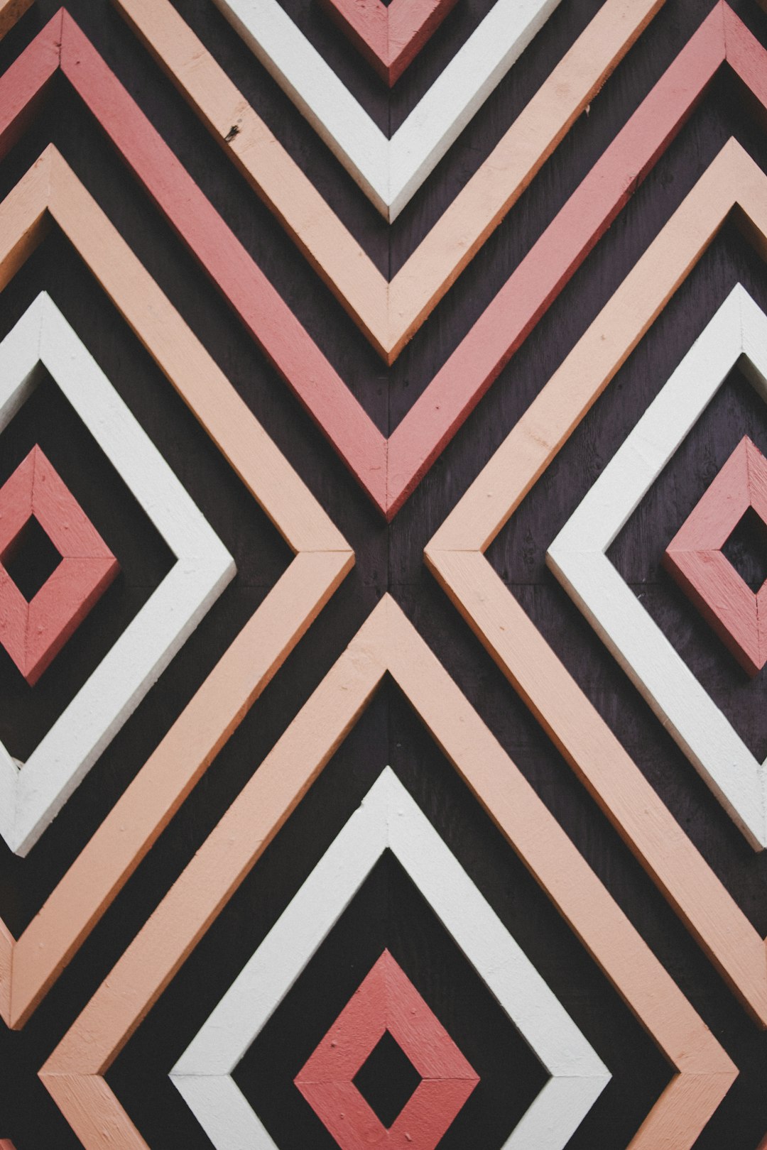 a close up of geometric wood wall art, symmetrical pattern, peach and black color palette, pink and white lines –ar 85:128