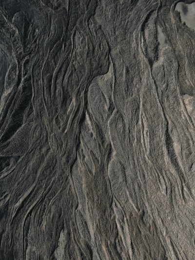 Aerial photography of the top view, closeup sand texture patterns on rocks and rivers, naturalistic landscape style, black and gray tones, dark background, wide angle lens, symmetrical composition, soft lighting, mysterious. High definition photography, high resolution. --ar 3:4