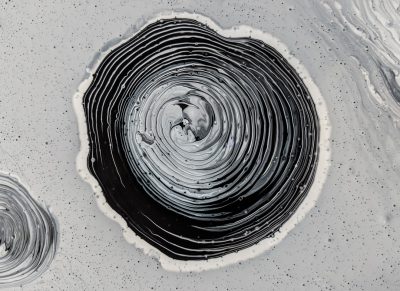 A black and white acrylic painting of circular swirls, paint splashes in the shape of an inkwell on top of it, on a grey background, in the style of a drone view. --ar 128:93