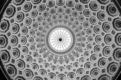 black and white photo of the ceiling dome inElyrealistic style, the architecture is a mix between classical greek and baroque styles. The patterns on it resemble hexagons with intricate designs, giving an overall symmetrical appearance. In its center stands a large circular window that allows light to filter through from above. The whole scene exudes elegance and grandeur as if looking up at something celestial or divine. --ar 128:85