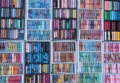 A grid of pastel crayon boxes, each filled with different colors, were arranged in rows and columns on the wall, creating an artistic display showing diversity in color palettes. --ar 16:11