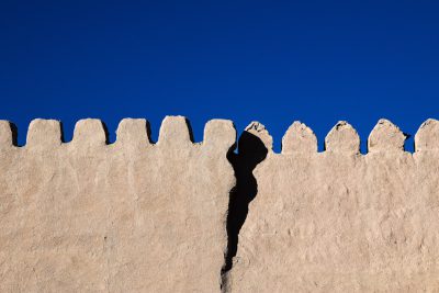 Photo of a wall with the shadow cast in the style of an ancient mud brick palisade in the desert against a blue sky, in a minimalist style, award winning photography --ar 128:85