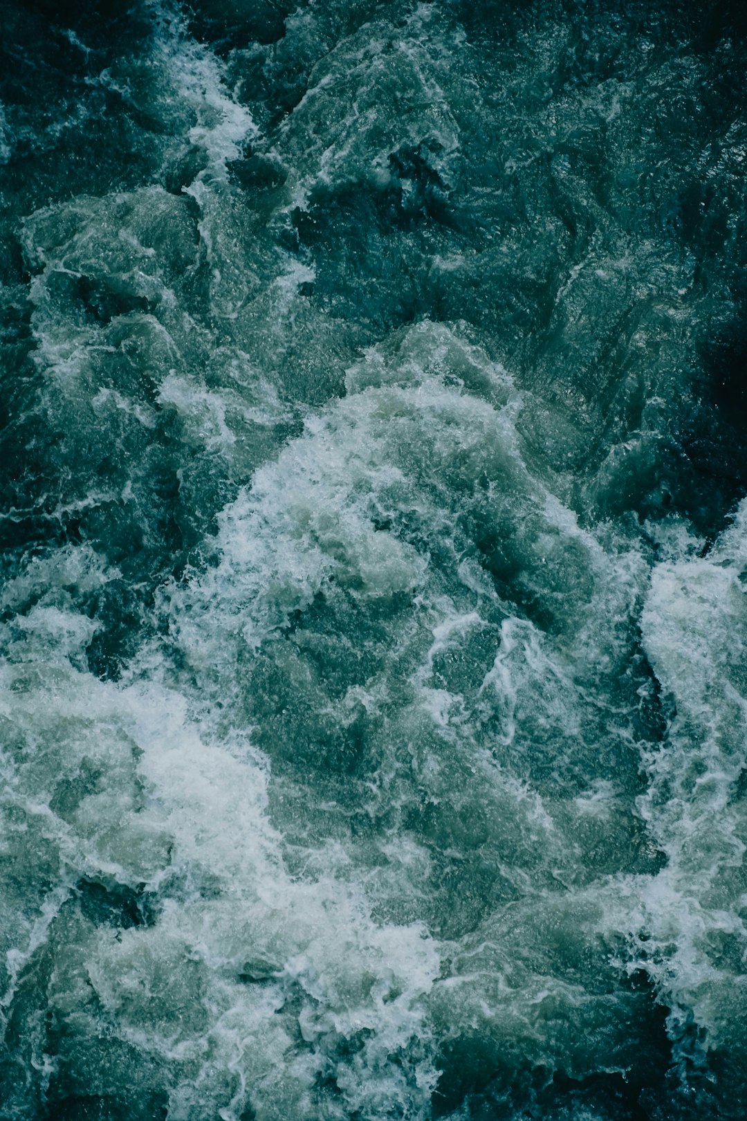 top down view of rough water, dark blue and green tones, photo realistic, cinematic, hyper real –ar 85:128