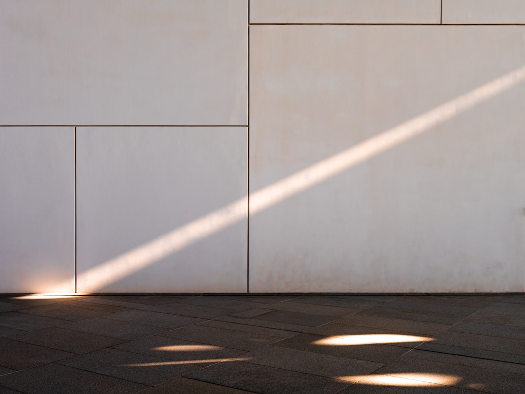 a white wall with a beam of light shining on it, the sun is setting and casting long shadows across an empty floor, modern architecture, architectural photography, architectural detail, detailed photography, cinematic –ar 4:3