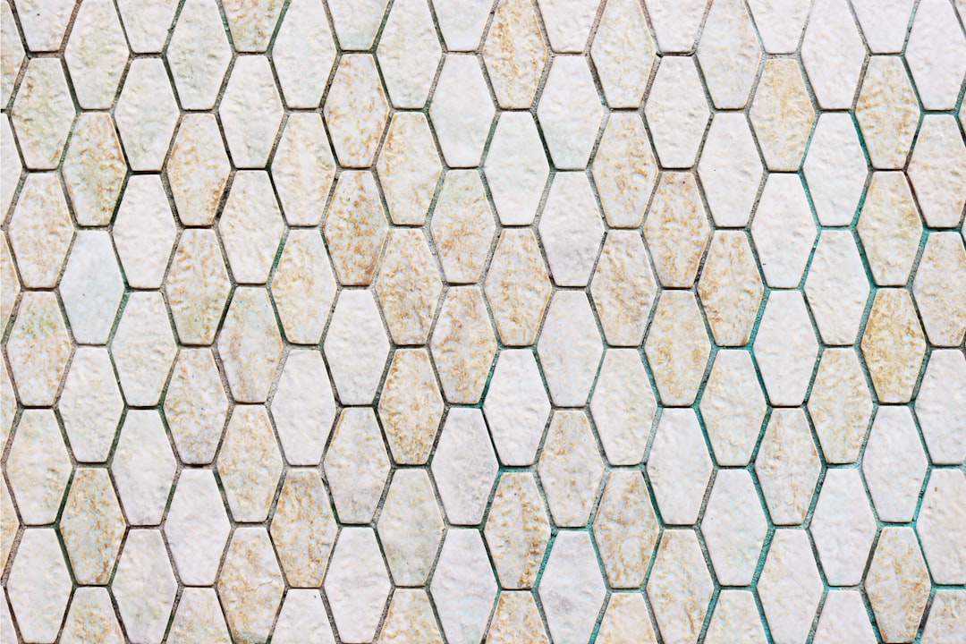 A hexagonal tile pattern of white and green tiles with a light brown color on the surface, in a top view, flat layout. The background features an elegant wall made from beige stone or marble. High resolution, professional photograph, sharp focus, studio lighting, crisp details in the style of HDR. –ar 128:85