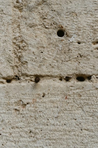 Closeup of small holes in the concrete wall, symbolizing Renaissance architectural details in the style of Renaissance. --ar 85:128