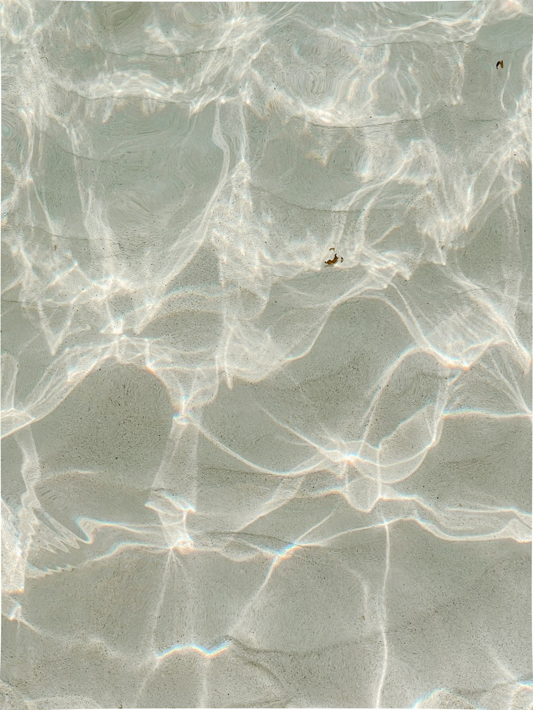 top down view of clear water, sand and light beams, subtle light colors, in the style of kodak film photography –ar 3:4