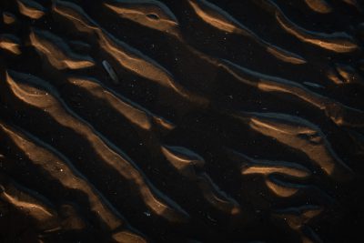 a dark sand texture with a pattern of ripples, at night, seen from above, photorealistic, cinematic lighting, high resolution photography --ar 128:85