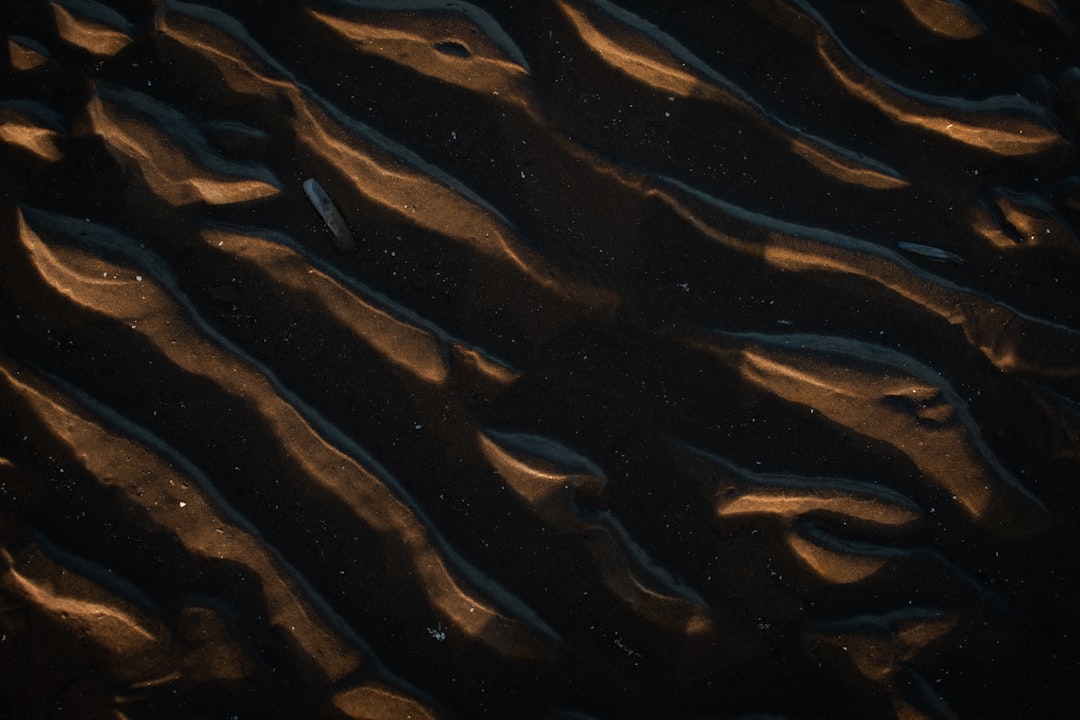 a dark sand texture with a pattern of ripples, at night, seen from above, photorealistic, cinematic lighting, high resolution photography –ar 128:85