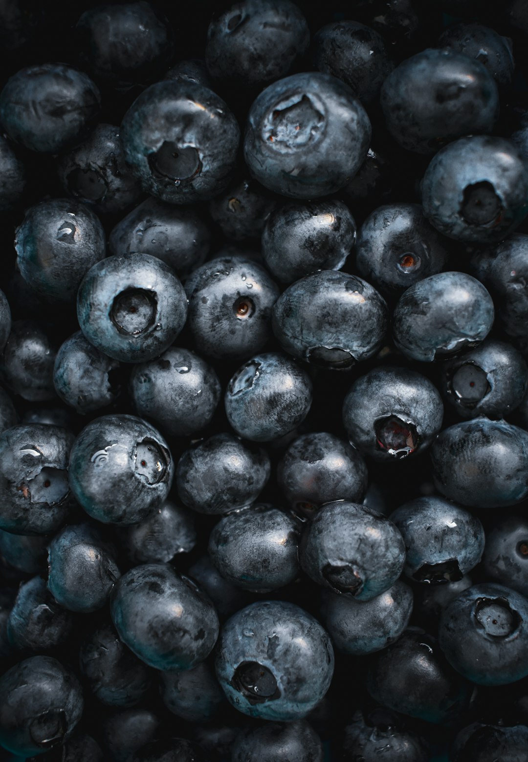 A pile of fresh blueberries, top down view, dark background, macro photography, hyper realistic in the style of professional color grading, high resolution photography with high contrast and depth of field for a hyper detailed and cinematic style. –ar 11:16