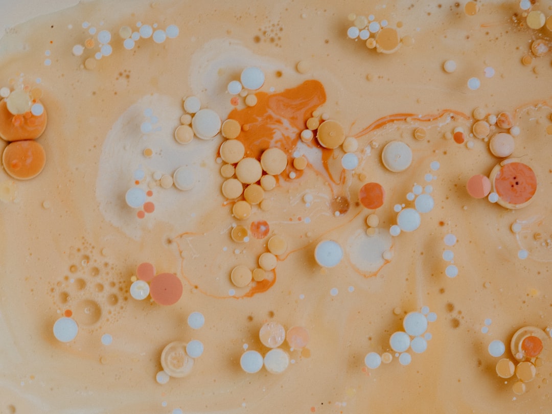 A photo of orange and white paint bubbles in beige milk, with swirls and patterns in an aerial view, in the style of abstract art. –ar 4:3