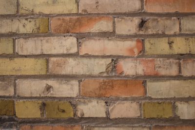 A closeup of an old, vintage brick wall with weathered red and yellow bricks, showcasing the texture and history behind it. The focus is on the intricate details such as worn edges, rough textures, and subtle color variations between each block. This detailed view highlights the beauty in aged materials, providing rustic charm to any design project. The photo shows an isolated background with ultra realistic detail in high resolution, capturing the style of vintage photography. --ar 128:85