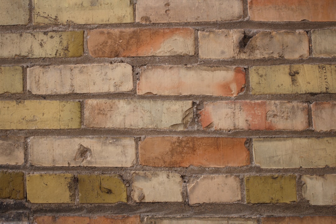 A closeup of an old, vintage brick wall with weathered red and yellow bricks, showcasing the texture and history behind it. The focus is on the intricate details such as worn edges, rough textures, and subtle color variations between each block. This detailed view highlights the beauty in aged materials, providing rustic charm to any design project. The photo shows an isolated background with ultra realistic detail in high resolution, capturing the style of vintage photography. –ar 128:85