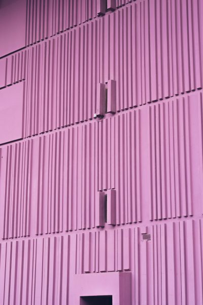 Pink metal wall with vertical lines, front view, pink purple color scheme, simple background, building facade photography, front closeup, symmetrical composition, bright light, minimalism, architectural details, architectural appearance, and sense of space. The building is made up of many small squares, which gives it an extremely interesting shape. This photo was taken by Sony Alpha A7 III camera. --ar 85:128