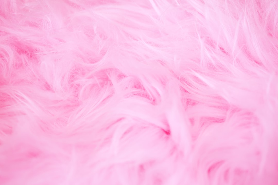 Pink fur background, soft and fluffy texture, closeup of pink plush material with detailed hair details, light tone background, shallow depth of field, high resolution photography, product shooting, professional studio lighting. –ar 128:85