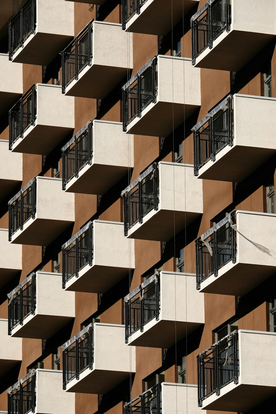 A photograph of apartment balconies arranged in a symmetrical pattern, architectural photography, archdaily, architectural detail, beige and brown. The photograph shows balconies arranged in the style of architectural photography for archdaily, with an architectural detail in beige and brown colors. –ar 85:128