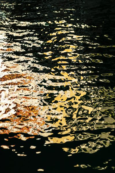 The water surface reflects the golden light, reflecting ripples on dark black background, reflection photography, Art Nouveau, high detail --ar 85:128