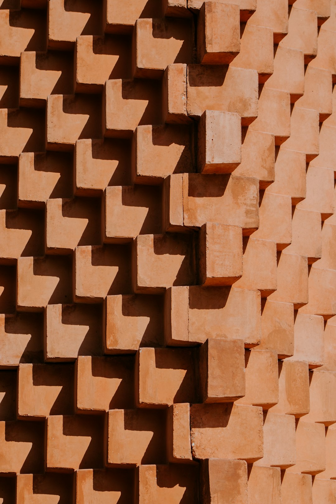 A terracotta wall made of interlocking blocks, each block shaped like an E Upward angle shot, with the focus on intricate geometric patterns and natural lighting. –ar 85:128