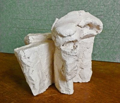 simple, small white clay sculpture of the upper body and head of an elephant sitting on its hind legs, on top is made with two different pieces of paper mache that together resemble trunk and ears --ar 64:55