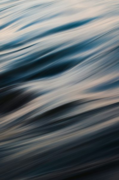 Abstract blurred sea waves at dusk, from a low angle view, with high resolution, high quality, and high detail. The HDR image shows dappled light with a soft focus and depth of field, captured through professional photography with sharp details in a full frame. --ar 85:128