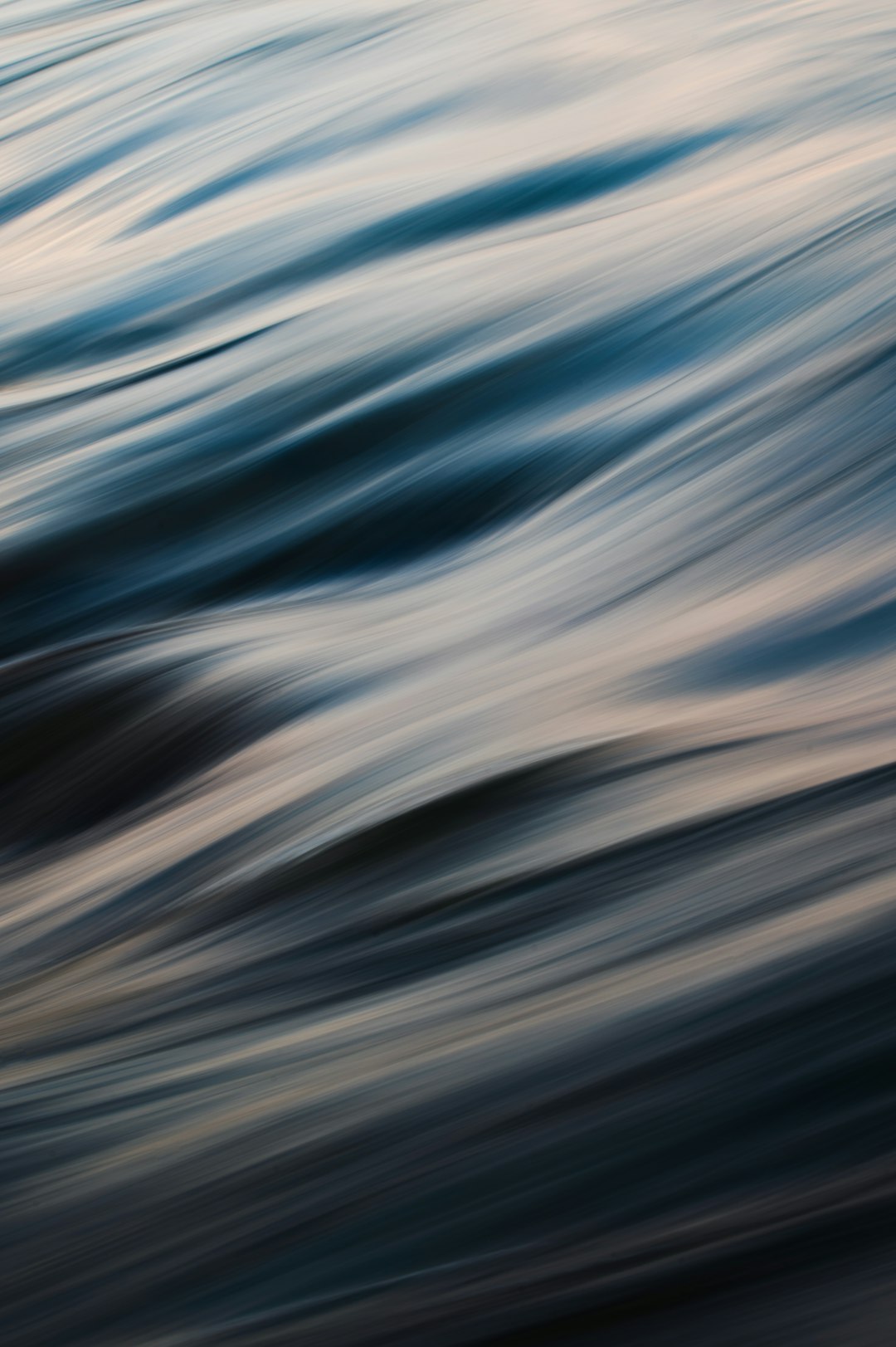 Abstract blurred sea waves at dusk, from a low angle view, with high resolution, high quality, and high detail. The HDR image shows dappled light with a soft focus and depth of field, captured through professional photography with sharp details in a full frame. –ar 85:128